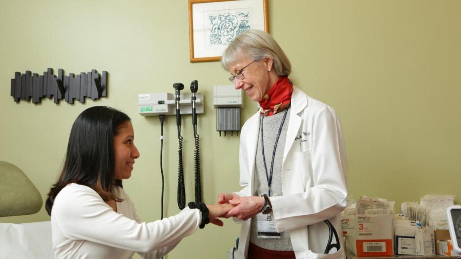 Spring time courtyard with pink flowers and lush green trees with doctors in white coats walking through beautiful weather.