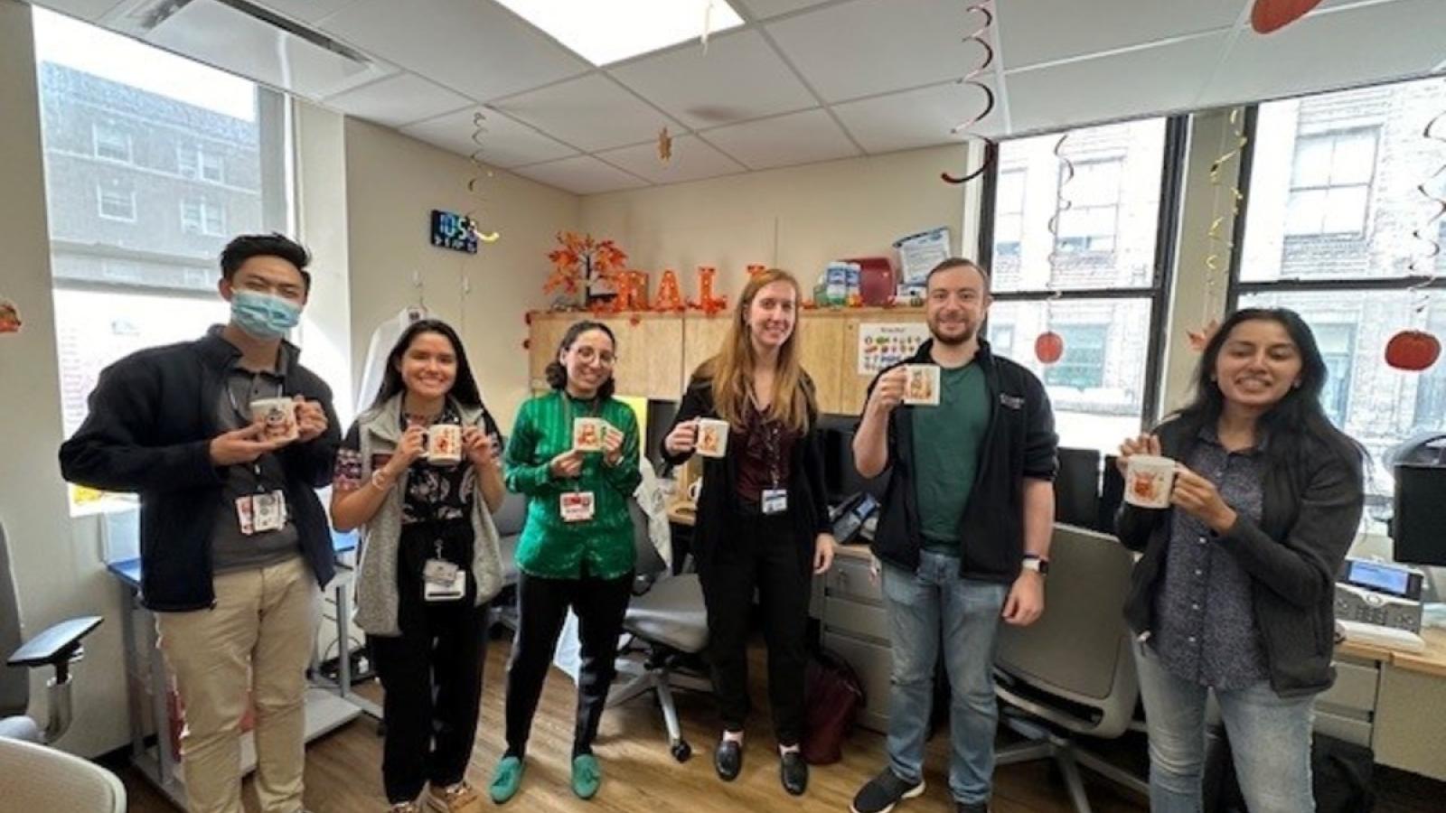 Fellows posing with fall themed mugs.