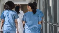 Healthcare professionals in scrubs walking down a hospital corridor together.